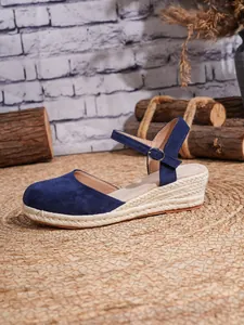 Primer plano de sandalias con cuña de gamuza azul con plataforma de esparto