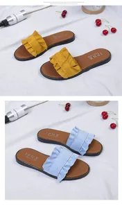 Detailed view of women's flat sandals with stylish ruffle wood ear trim in yellow and blue