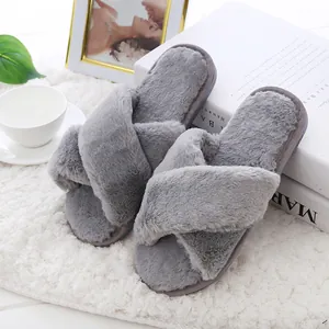Close-up detail of soft grey faux fur cross-strap house slippers in a cozy setting
