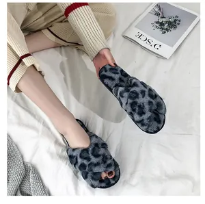 Detail of leopard print faux fur cross strap slippers on a white blanket background.