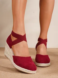 Primer plano de alpargatas con cuña de ante burdeos con correas elásticas cruzadas