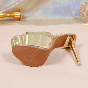 Dettaglio dei tacchi a spillo dorati da 16 cm con una suola marrone antiscivolo.