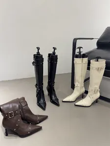 Classic vintage pointed-toe tall boots with studded buckle straps in black, beige, and brown