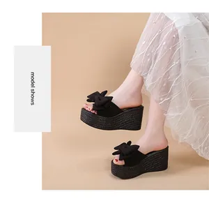 Elegante schwarze Keilsandaletten mit großer Schleife, getragen von einem Model.