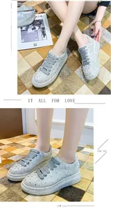 Detail view of white rhinestone platform sneakers worn by a model on a checkered mat.