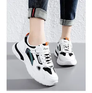 Close-up van stijlvolle witte chunky sneakers met zwart mesh en oranje accenten.
