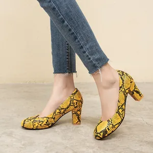Side view of yellow snakeskin pattern round toe pumps with block heel