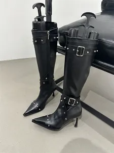 Side view of black leather knee-high boots featuring silver studs and buckle details.