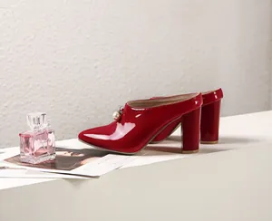 Detailed view of red patent leather chunky heel mules with elegant pearl charm accents.