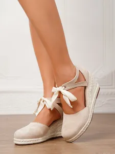Vista detallada de alpargatas con cuña beige para mujer con elegantes cintas blancas