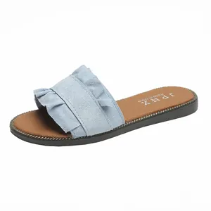 Close-up of light blue ruffled slides with chain-trimmed sole and brown insole.