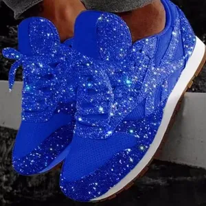 Close-up of vibrant blue sequined sneakers with dazzling rhinestone accents and chunky soles.