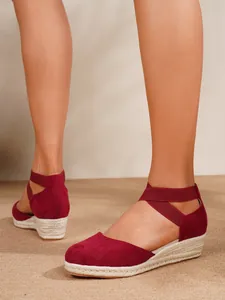 Primer plano detallado de sandalias de cuña en ante rojo con correas