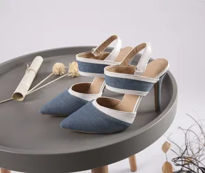 Elegantes stilettos de mezclilla con punta fina y ribete blanco en mesa gris chic.