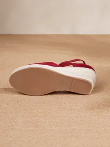 Detalle de la suela de goma y la cuña de yute trenzada en sandalias rojas de mujer