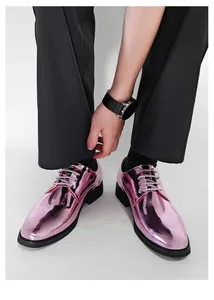 Detail of shiny pink metallic men's dress shoes with silver laces on a model.