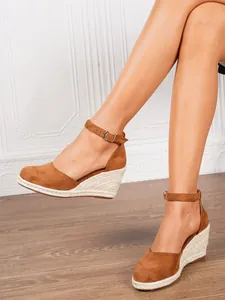 Detailed macro shot of brown suede wedge espadrilles with woven soles and ankle straps