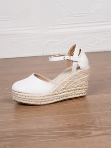Detail von weißen Espadrille-Keilsandalen mit geschlossener Zehenpartie und Seilplateau.