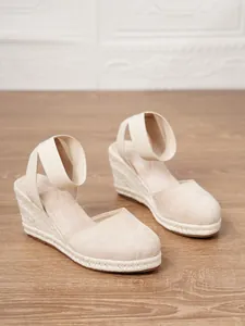 Primer plano de sandalias de cuña beige para mujer con suelas de esparto de yute clásicas