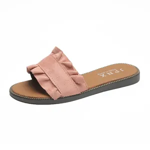 Detail view of pink suede flat slide sandals featuring an elegant ruffled strap design
