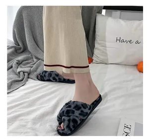 Close-up of leopard print fuzzy cross-strap slippers in a cozy home setting