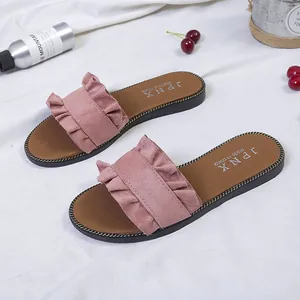 Detail view of stylish pink ruffled flat slide sandals for women's summer beach wear.