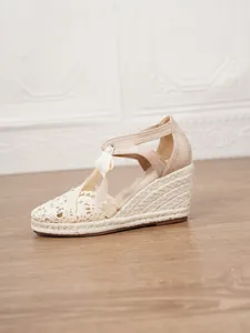 Vista lateral detallada de sandalias de cuña de ganchillo beige con suela de yute