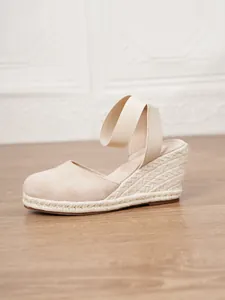 Vista lateral de sandalias con cuña beige para mujer con suela de esparto trenzada