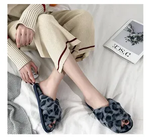 Detailed view of woman wearing fuzzy leopard print cross strap house slippers on white linen