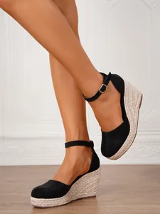 Elegantes sandalias de cuña negras de punta cerrada con tacón de esparto y correa.
