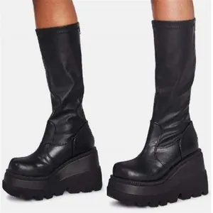 Close-up detail of black gothic platform mid-calf boots with chunky wedge soles.