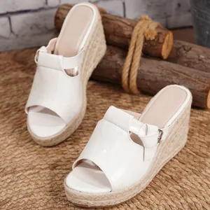 Stylish white crocodile-embossed wedge sandals featuring a natural straw-woven platform heel.