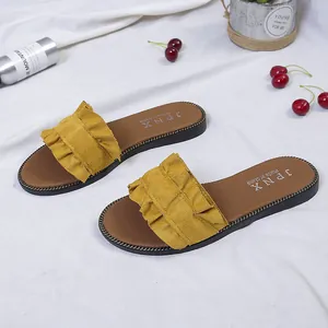 Close-up detail showing the yellow ruffle design and decorative metal chain edge trim on sandals