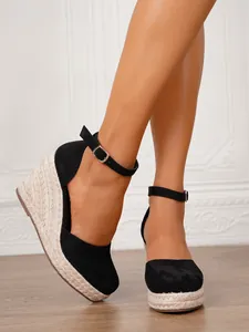 Vista detallada de sandalias de cuña en ante negro con plataforma de yute y correas