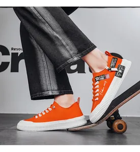 Detail of men's orange canvas skate shoes with thick white soles on a skateboard