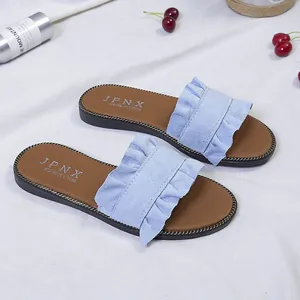 Close-up detail of light blue ruffle flat sandals with elegant metal chain trim on the sole