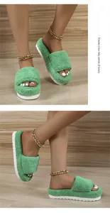 Detailed view of fashionable green fluffy terry cloth slippers with a thick white platform sole.