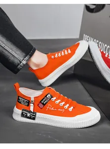 Macro view of orange canvas sneaker featuring thick white sole and decorative tags.