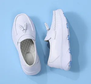 Seiten- und Draufsicht auf weiße Leder-Pflegeschuhe mit Quasten auf blauem Grund