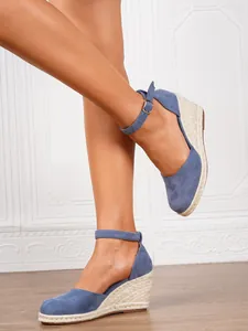 Detailed side view of blue suede wedge espadrilles with ankle straps on model's feet