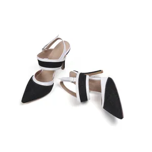 Vista detallada de zapatos de tacón de mezclilla negra con punta fina y ribete blanco.