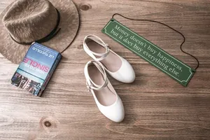 Top-down view of white double-strap Mary Jane shoes on a rustic wooden floor