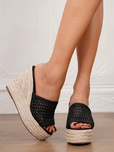 Detalle de sandalias de cuña negras con tiras tejidas y plataforma de paja mujer