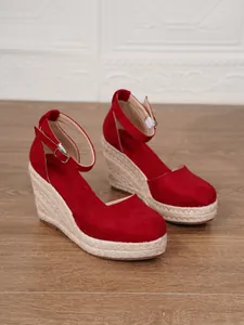 Sandalias rojas de cuña con puntera cerrada, plataforma de esparto y tira al tobillo.