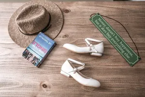 Elegant white Mary Jane shoes featuring criss-cross straps and decorative pearl charm detail
