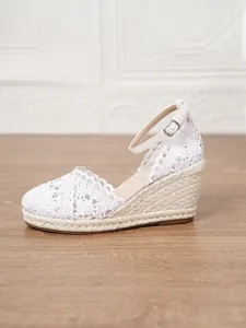 Detalle de sandalias de cuña con encaje blanco y suela de paja de verano para mujer.