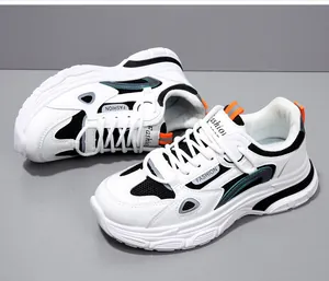 Close-up van stijlvolle witte dames chunky sneakers met dikke zolen en oranje accenten.
