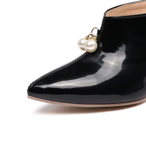 Close-up of black patent leather pointed mule with elegant double pearl bead charms