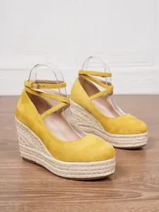 Vista detallada de sandalias de cuña tipo alpargata en ante amarillo con plataforma de paja.