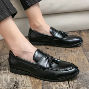 Elegantes mocasines de cuero negro para hombre con un detalle clásico de borla decorativa.